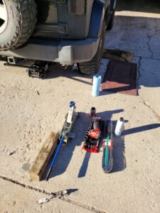 Mobile mechanic near me in Denver with tools including a jack, impact wrench, and socket set laid out on a driveway