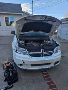 White van with hood open for repair in a Fort Worth driveway, mechanic’s tool bag nearby, serviced by AutoFordable Mobile Mechanics.