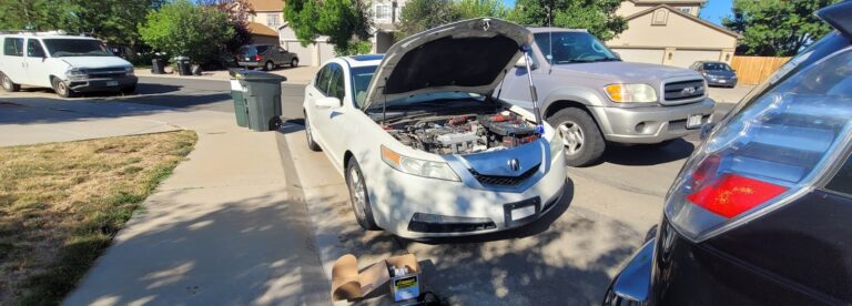 Mobile mechanic in Denver repairing a white Acura on a residential street