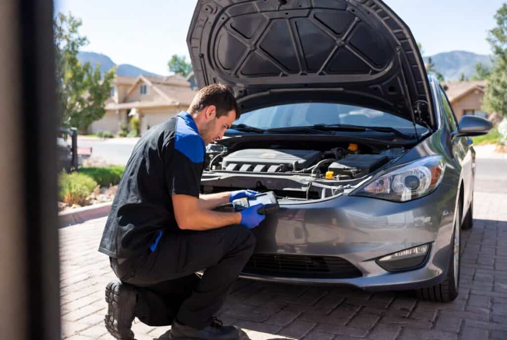 Professional mobile mechanic inspecting a car engine outdoors, providing on-site auto repair and maintenance services at your location.