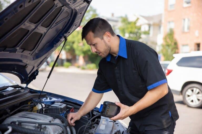 Mobile mechanic inspecting car engine with diagnostic tool near Denver, providing fast auto repair services.